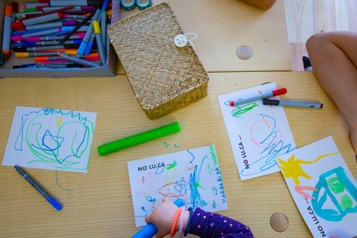 Mesa com canetas e folhas com desenhos feitos por crianças