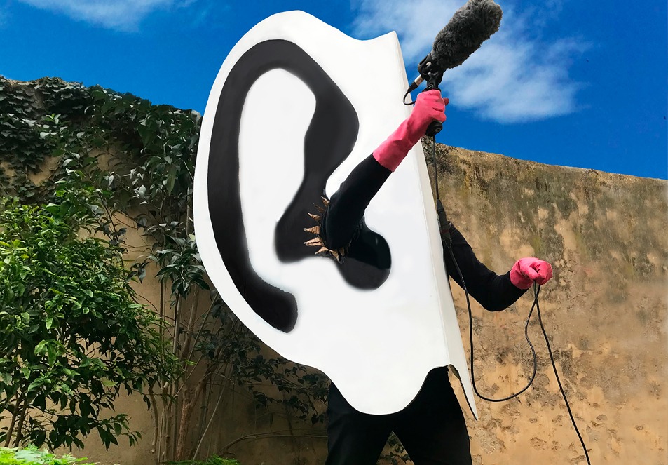 Pessoa vestida de orelha gigante com um microfone na mão