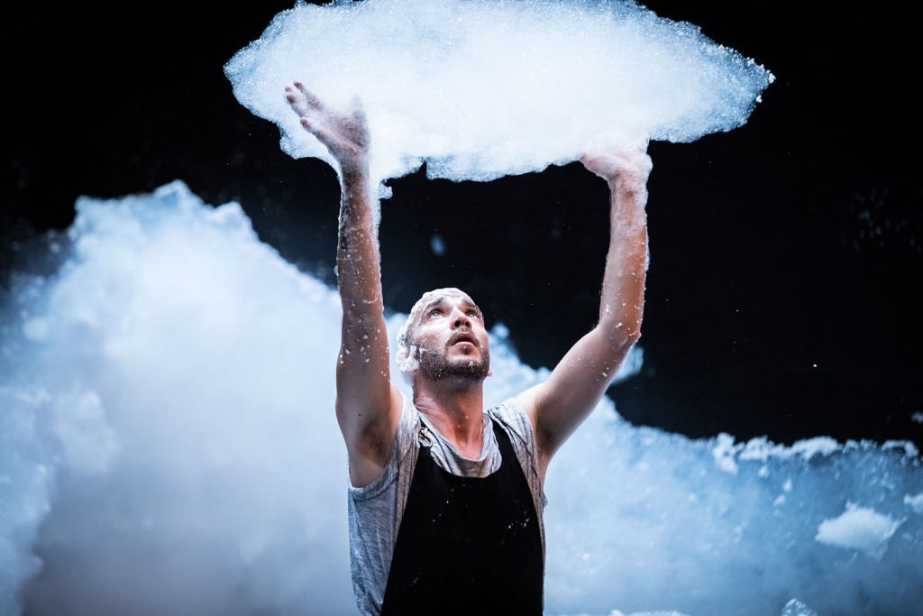Homem de braços no ar segura espuma em forma de nuvem