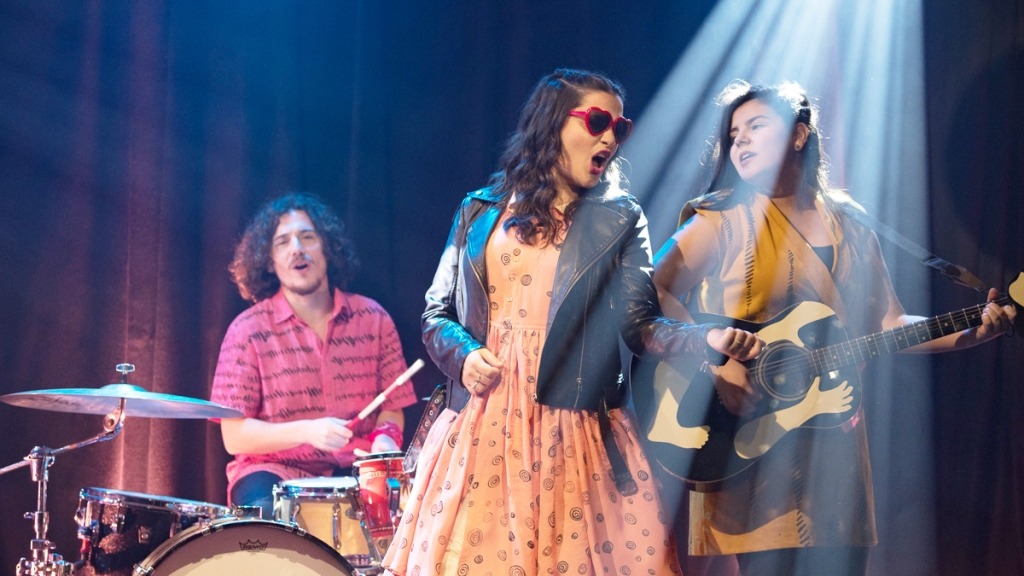 Três músicos do projeto O Gato Pintor 
 (duas mulheres e um homem) em cima do palco durante um concerto.