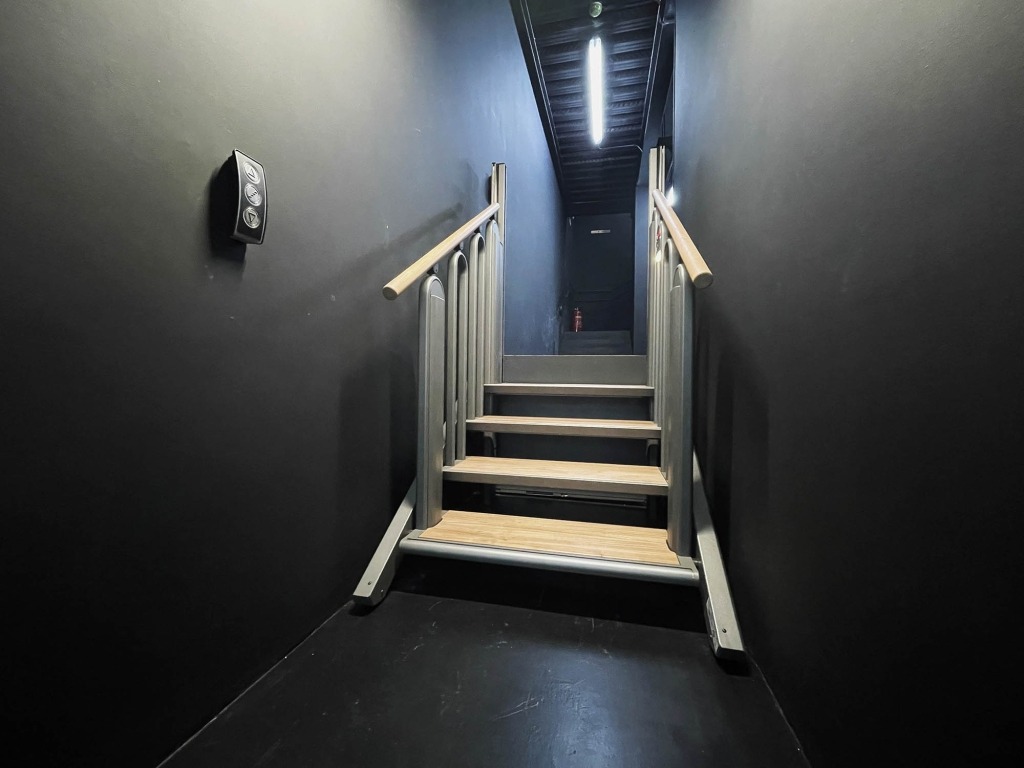Escadas com 4 degraus num corredor de paredes pretas.