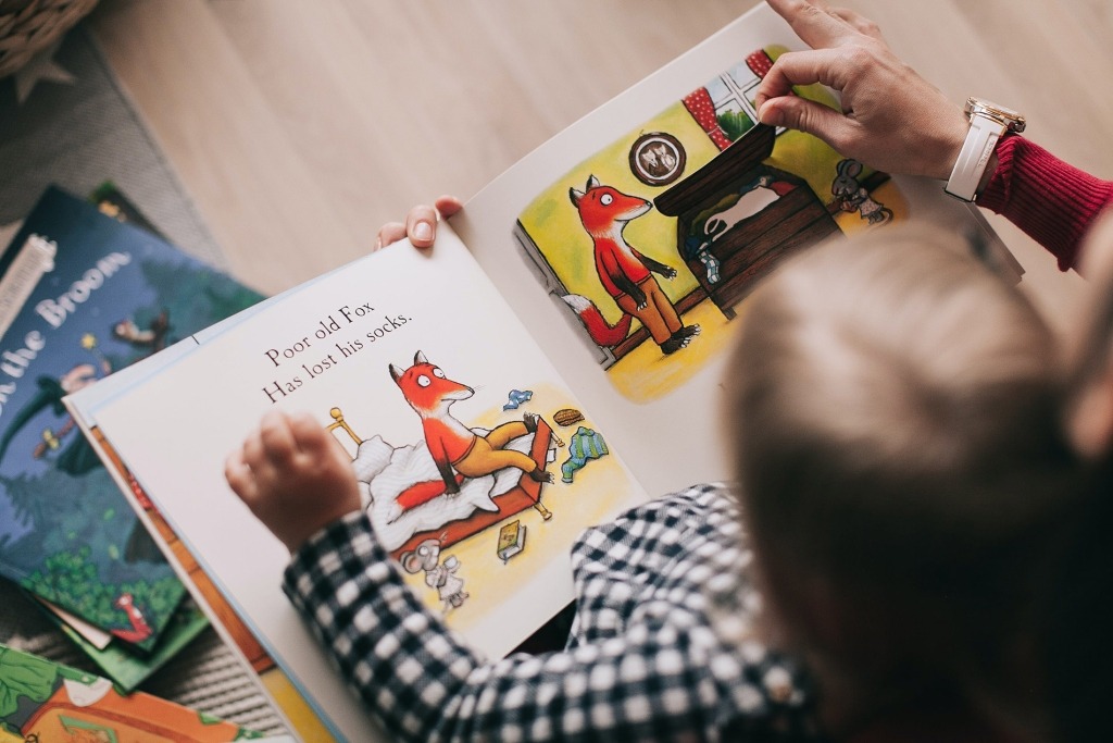 Criança segura um livro ilustrado ao colo.
