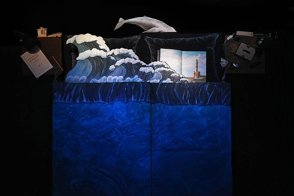 Cenário simula uma cama. Na zona das almofadas há elementos estranhos como ondas, baleias ou faróis.