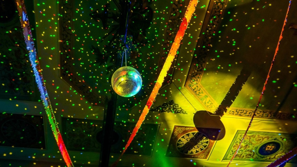 Fotografia de teto de festa com bola de espelhos, fitas de plumas e efeitos luminosos.