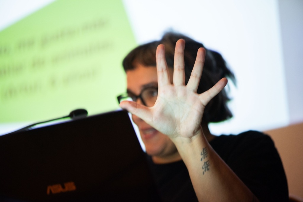 Fotografia da orientadora Joana Rita Sousa com a mão aberta à frente da cara.