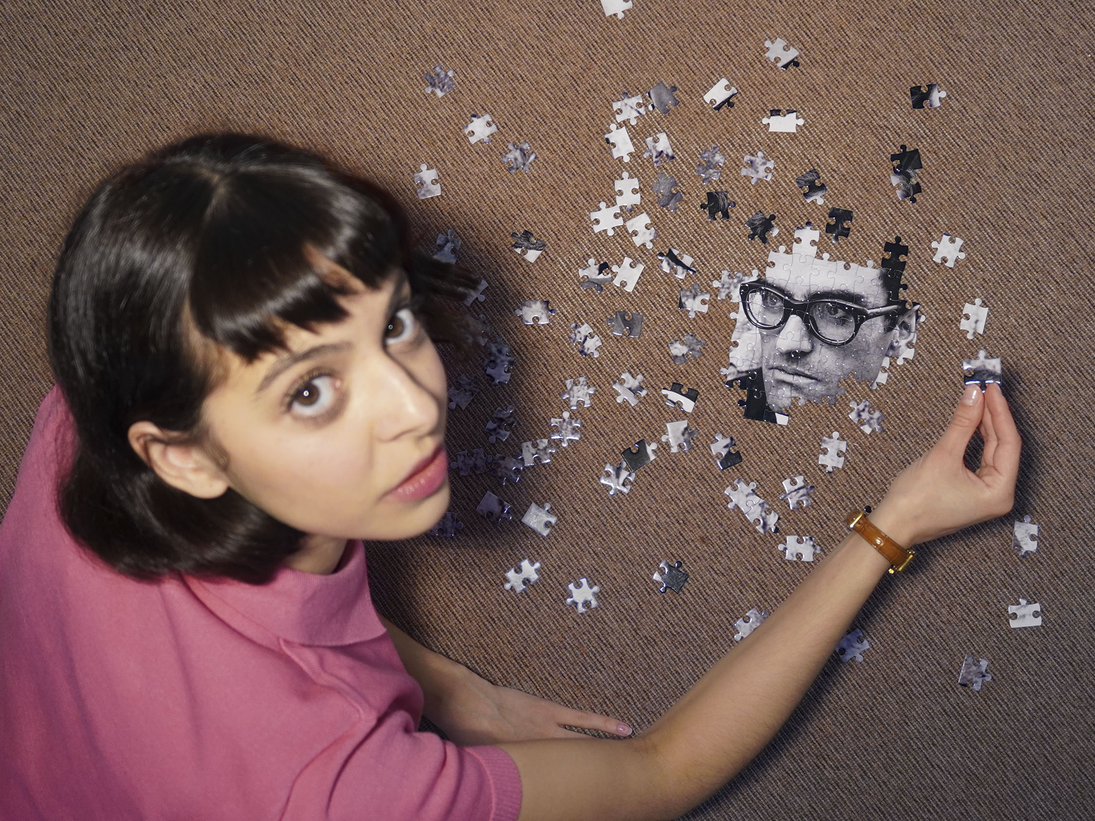 Actress Malu Vilas Boas looking up while doing a puzzle with Alexandre O'Neill's face