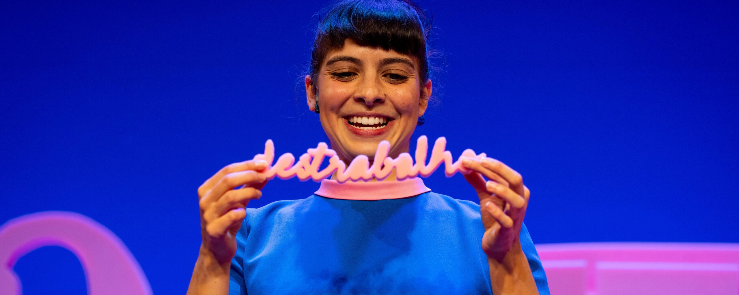 Atriz vestida de azul segura a palavra 